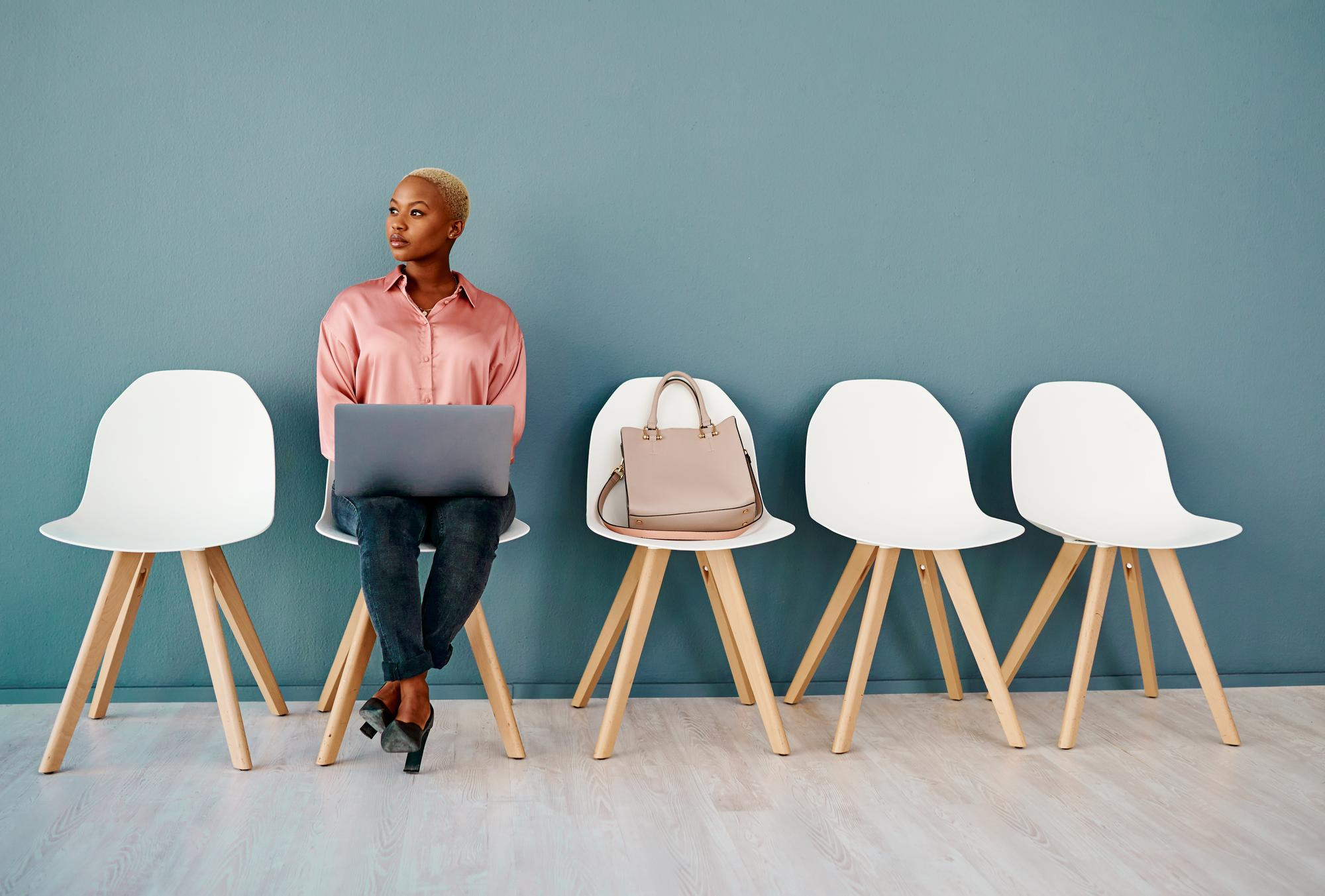 lady sitting on chair with laptop waiting for interview